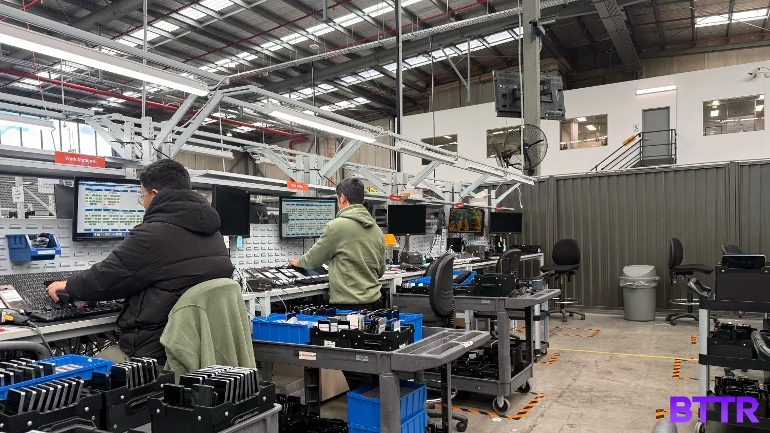 Two workers running comprehensive tests on used phones at the Assurant warehouse.