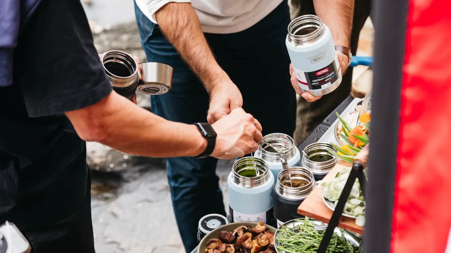 People packing food into Thermos food jars.