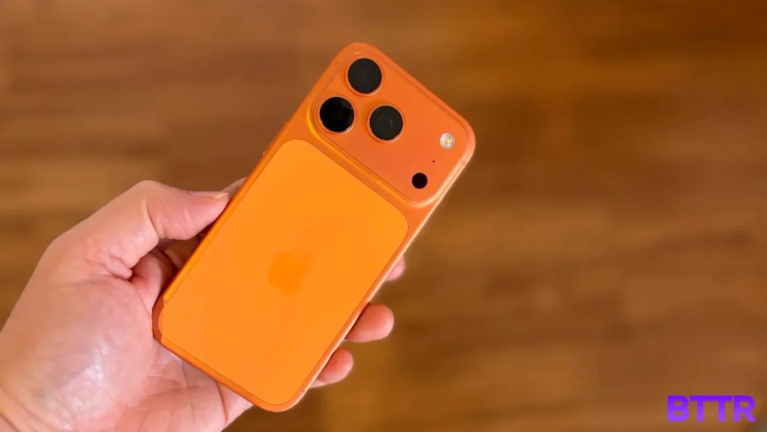 The iPhone 17 Pro in orange being held in the hand.
