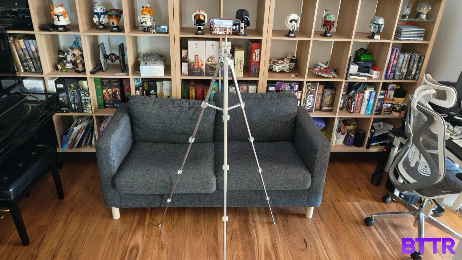 A zoomed out shot of the Belkin Stage Creator Kit tripod at full height in front of a lounge and bookshelf