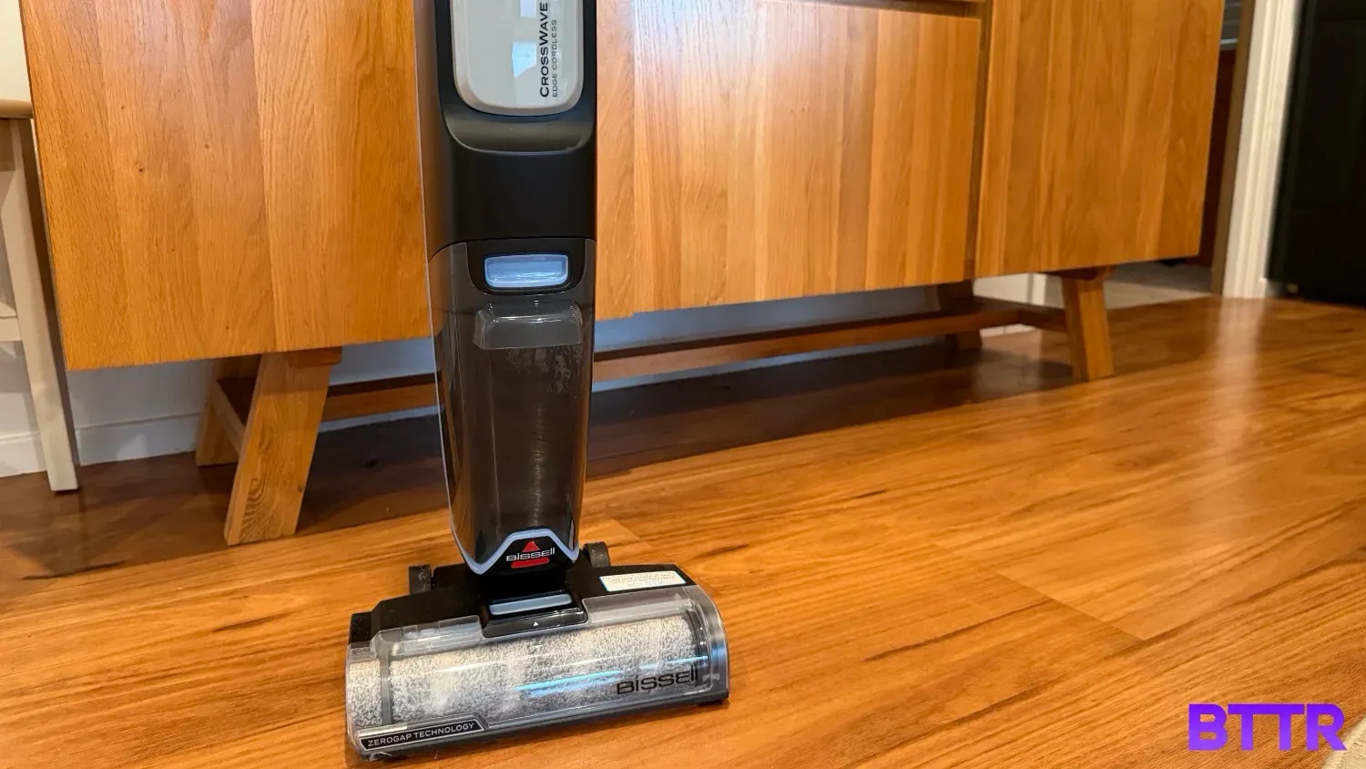 The Bissell Crosswave Edge Cordless on wood floors in front of wood furniture