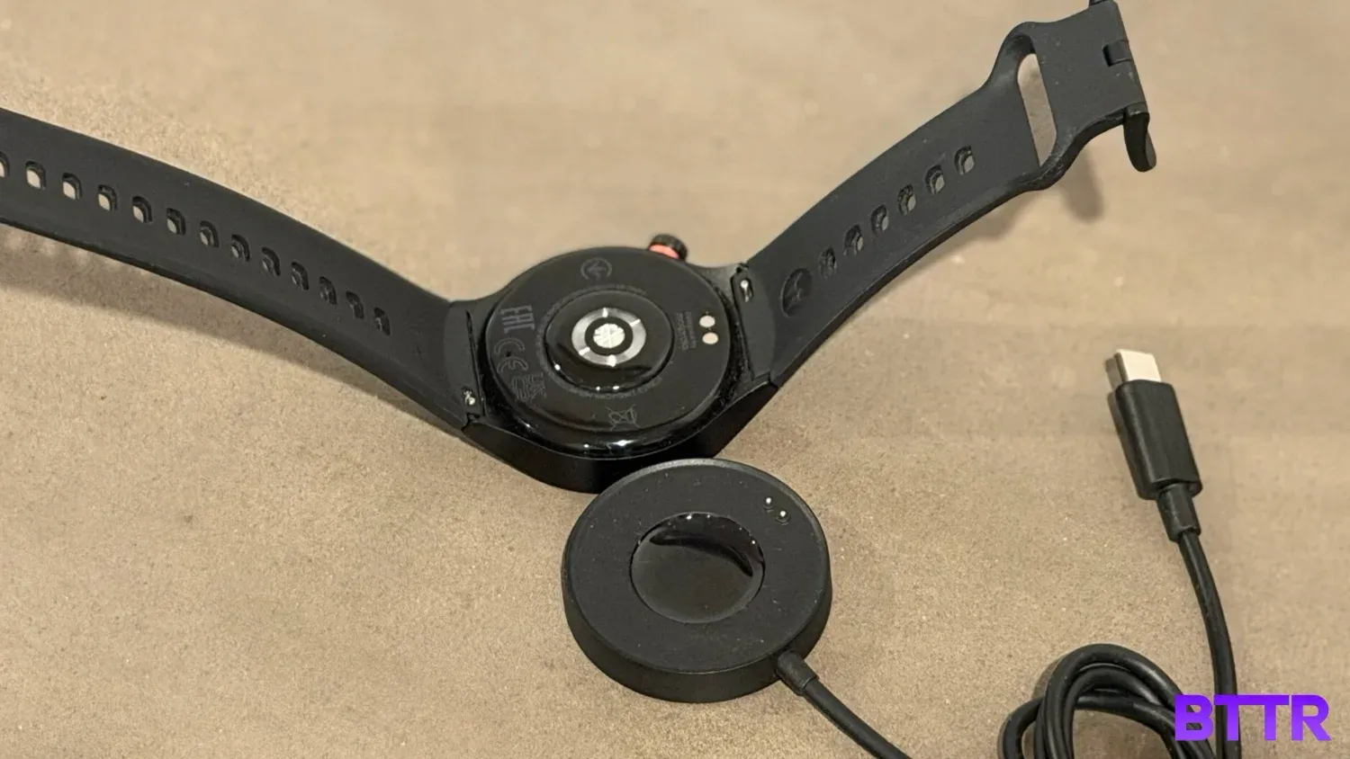 the moto watch upside down next to its large charger on a concrete table