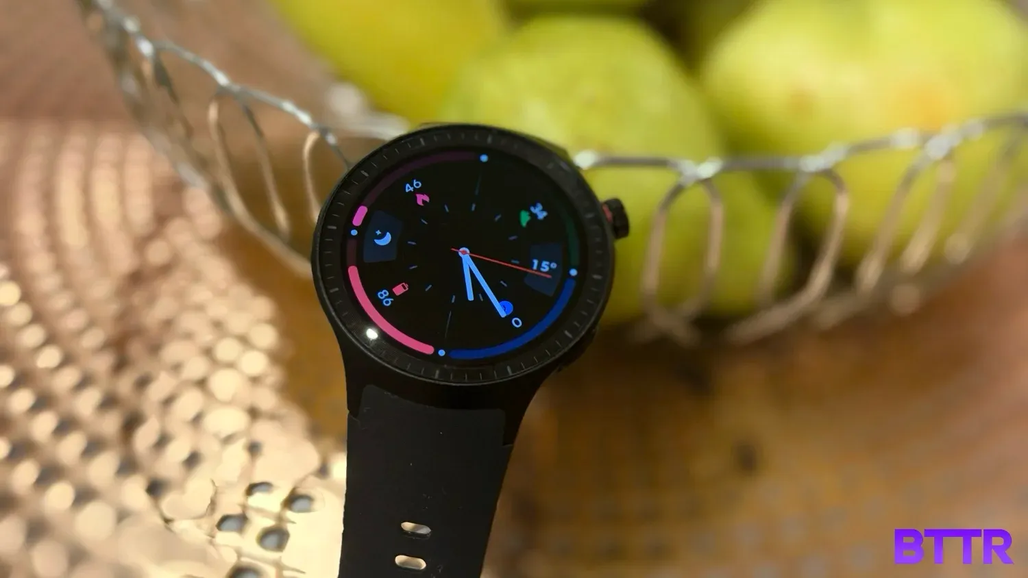 The moto watch on a bowl with some pears in the background