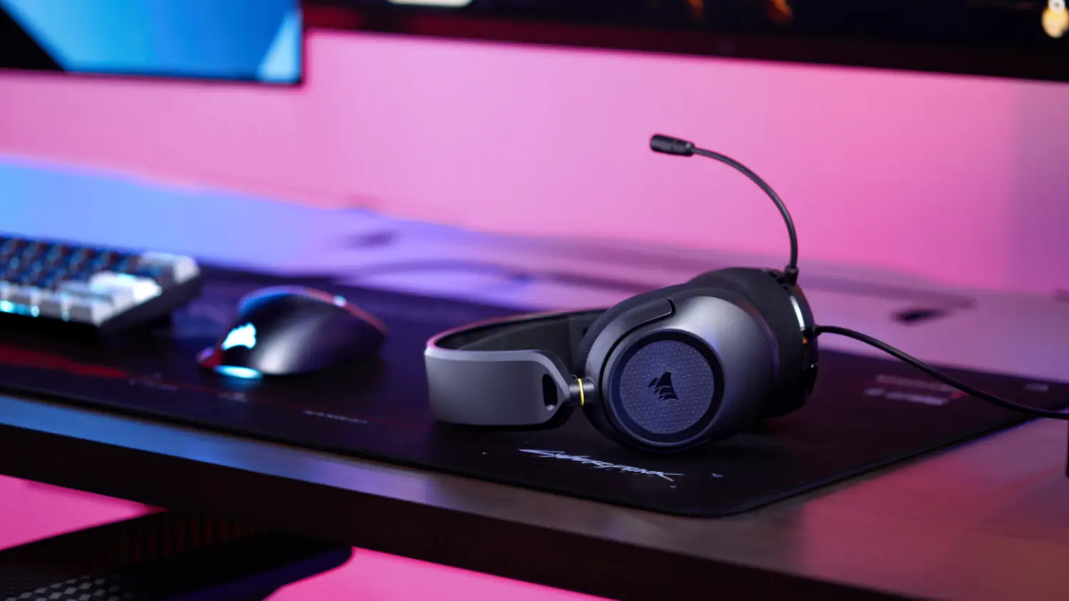 The wired HS35 v3 headset from corsair on a desk next to a mouse with pink ambient lighting