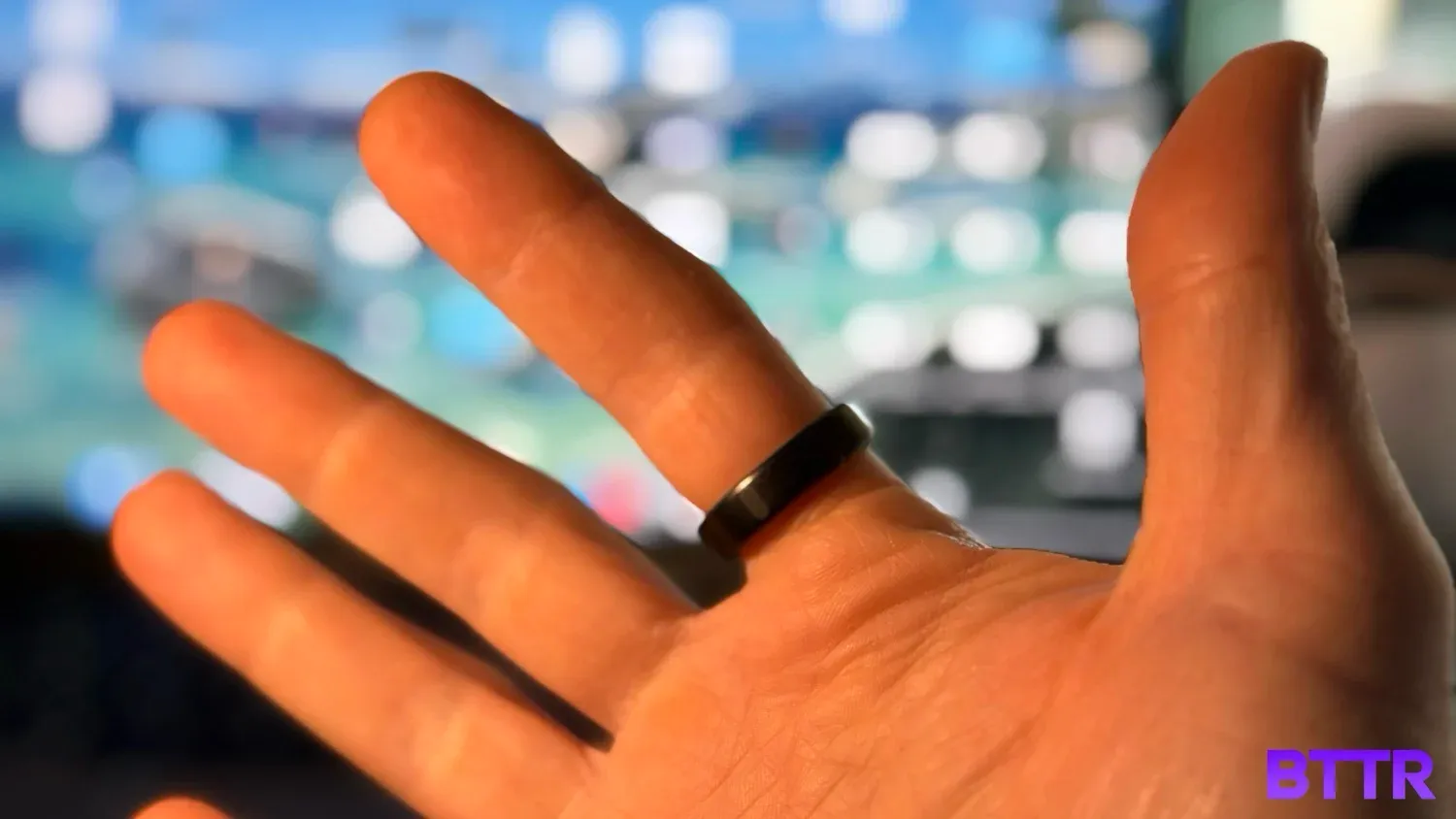 Wearing the Oura Ring 5 on an index finger in front of a laptop screen