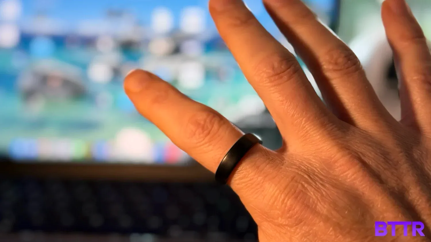 Wearing the Oura Ring 5 on an index finger in front of a laptop screen