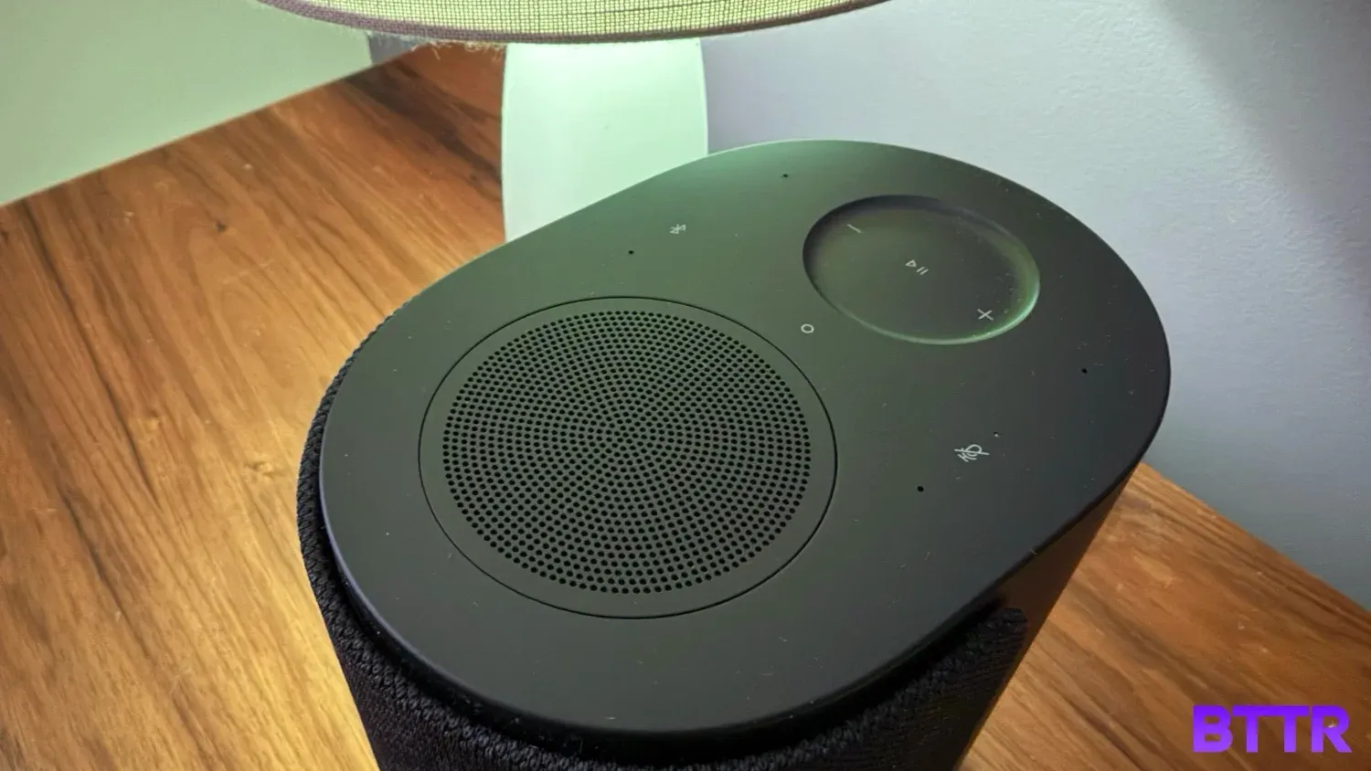 Looking at the top of the The Black Bose Lifestyle Ultra speaker on a bedside table with a lamp