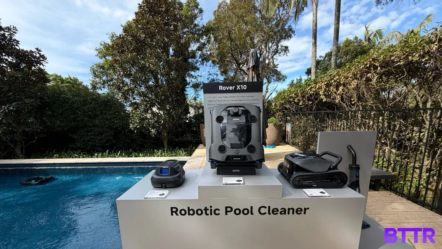MOVA's pool cleaner lineup in front of a pool on a stand