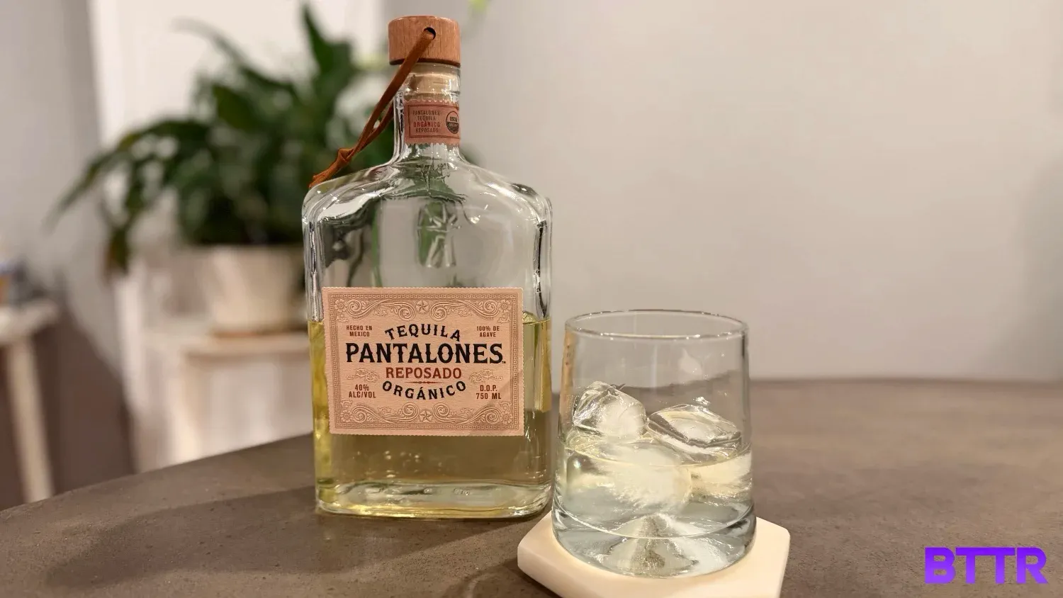 The Pantalones Reposado tequila in a glss with ice next to the bottle