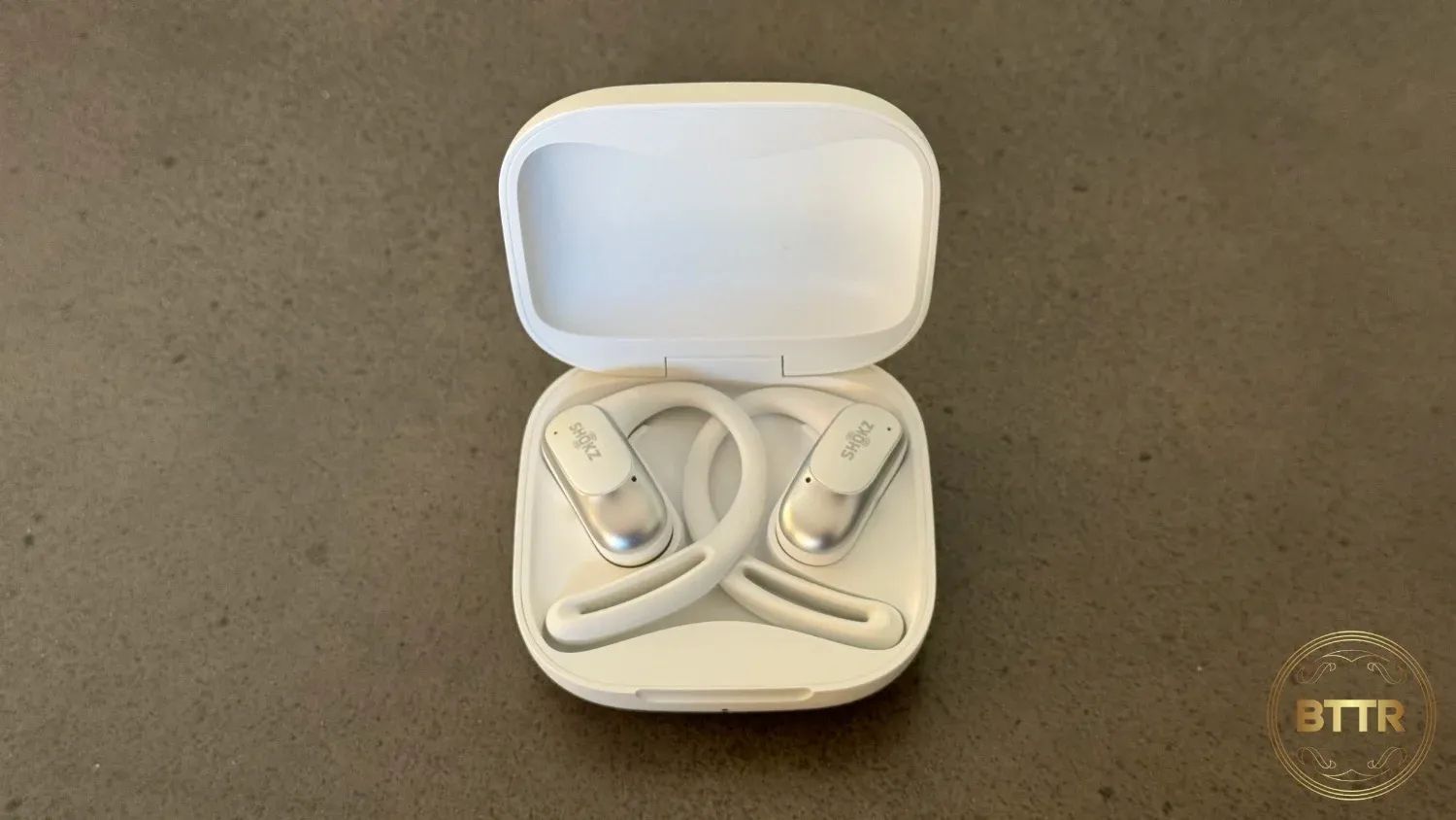 The Shokz Openfit air in the case on a concrete surface