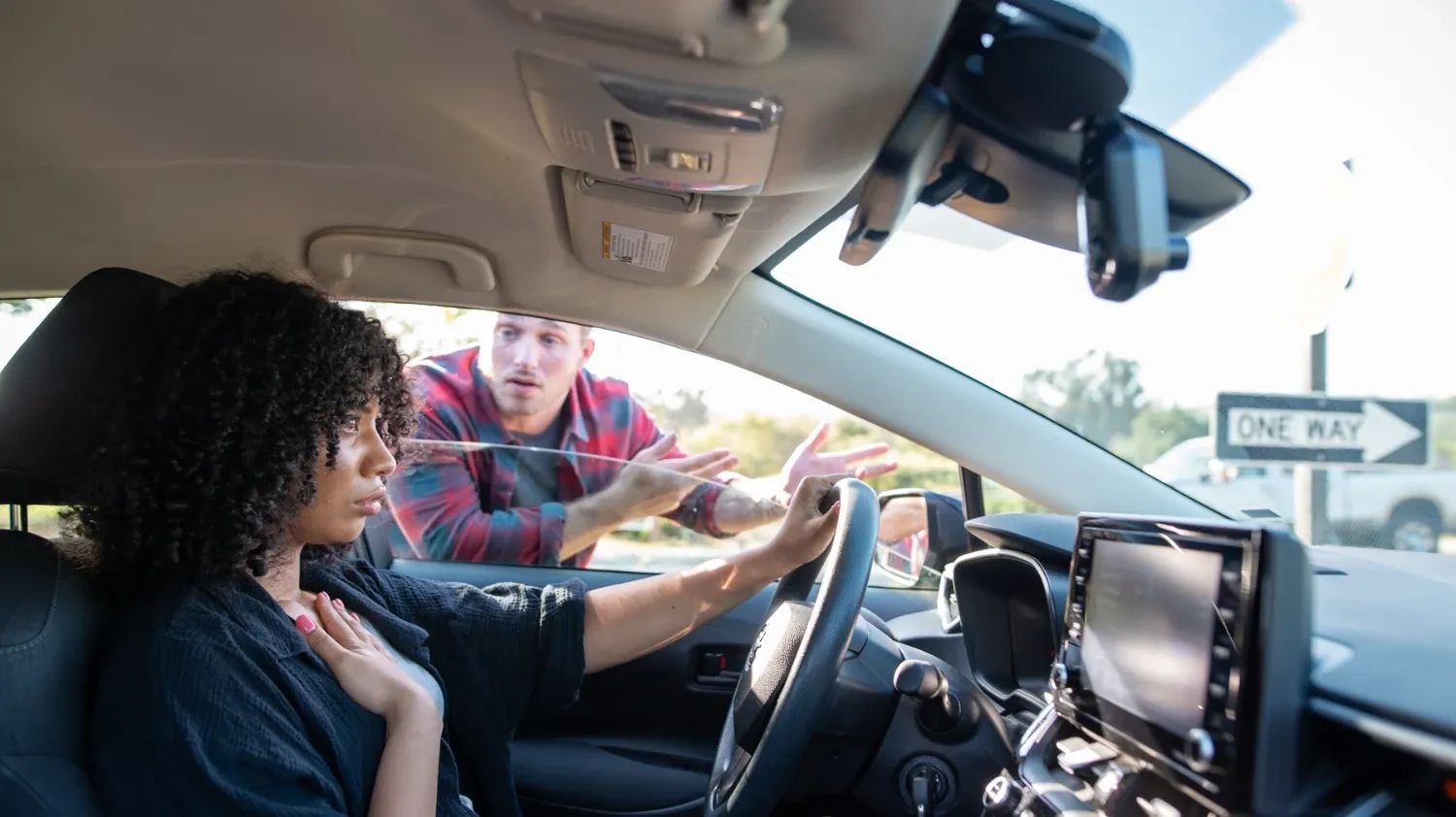 A woman in a car looking anxious as a man tells her off through her window