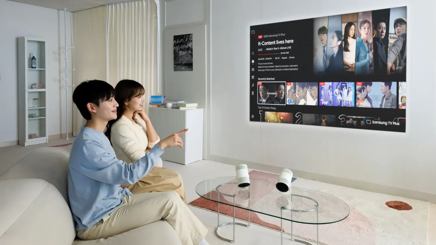 A couple in a loungeroom using the Freestyle+ projector on a wall from their coffee table