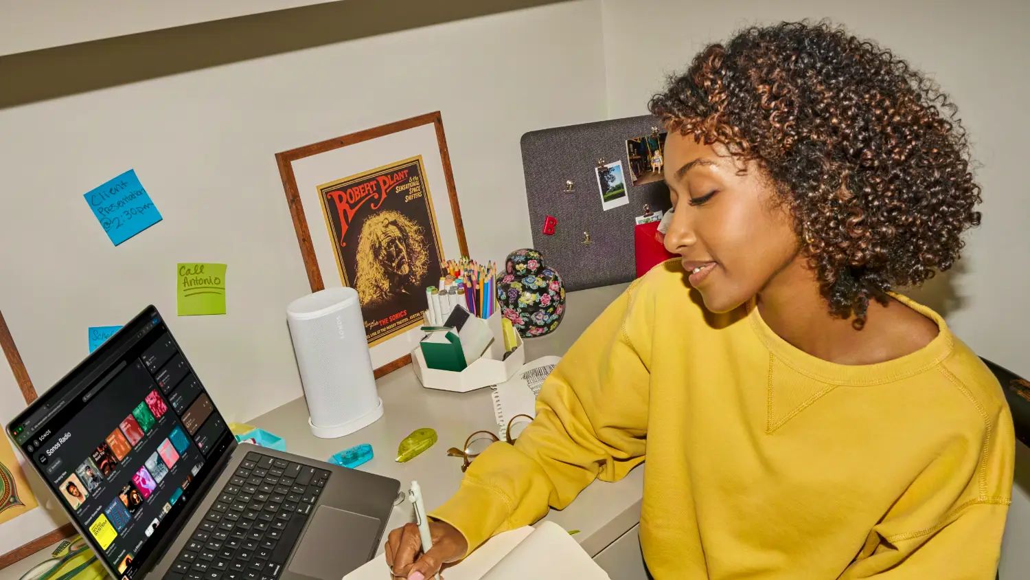 A girl at a (pretty messy) desk with a laptop and the Sonos Play 