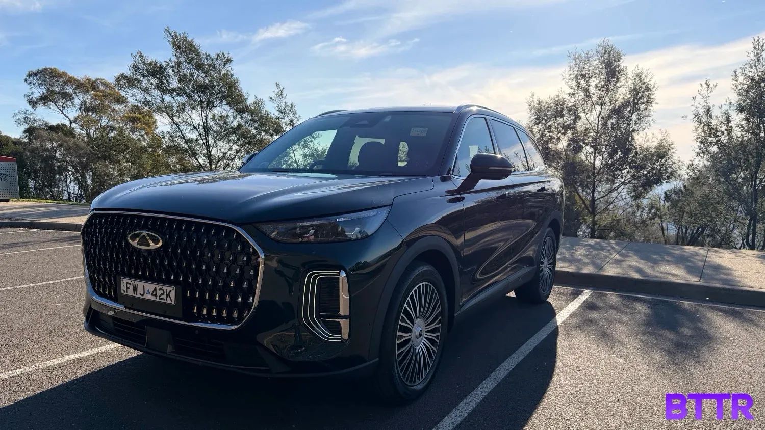 The Chery Tiggo 9 in a parking space in front of trees