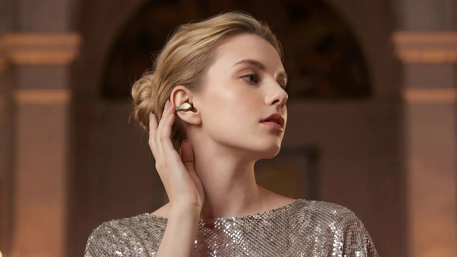 A woman wearing a shiny dress and the Enco Clip2 earbuds