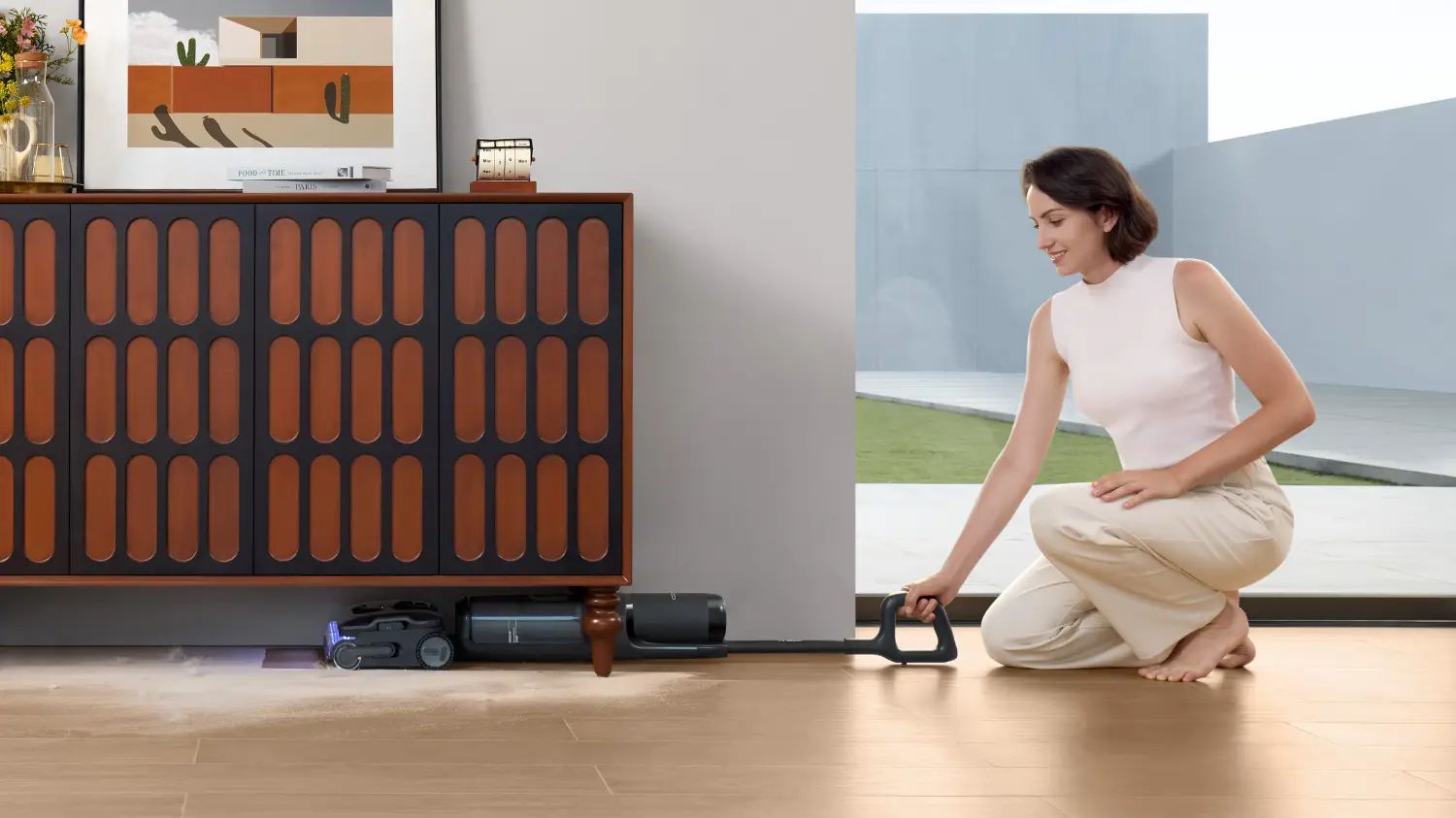 A woman cleaning under a cabinet with the FLOOR ONE i7 STretch steam from Tineco
