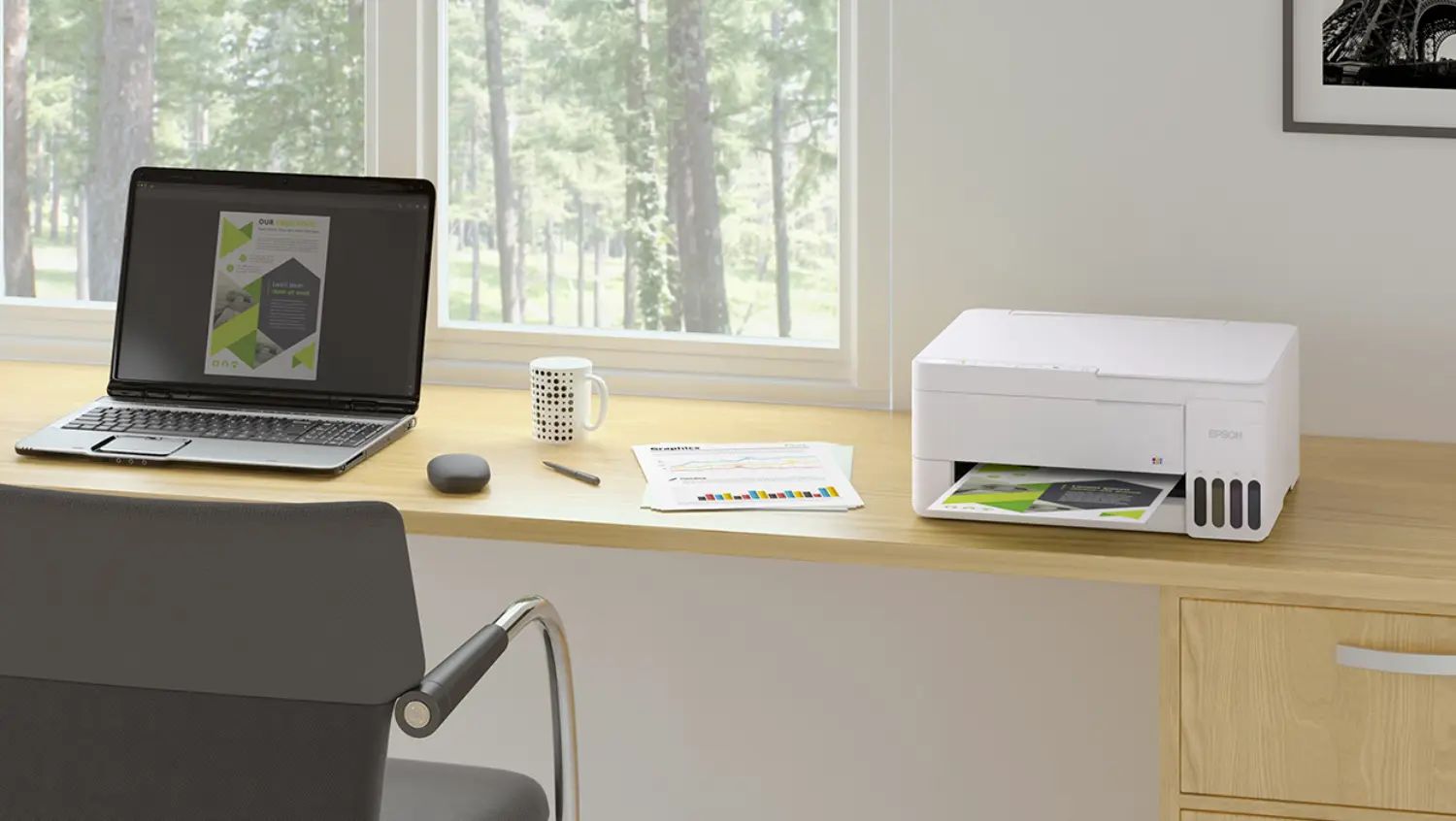 An Epson Ecotank printer on a desk near a laptop