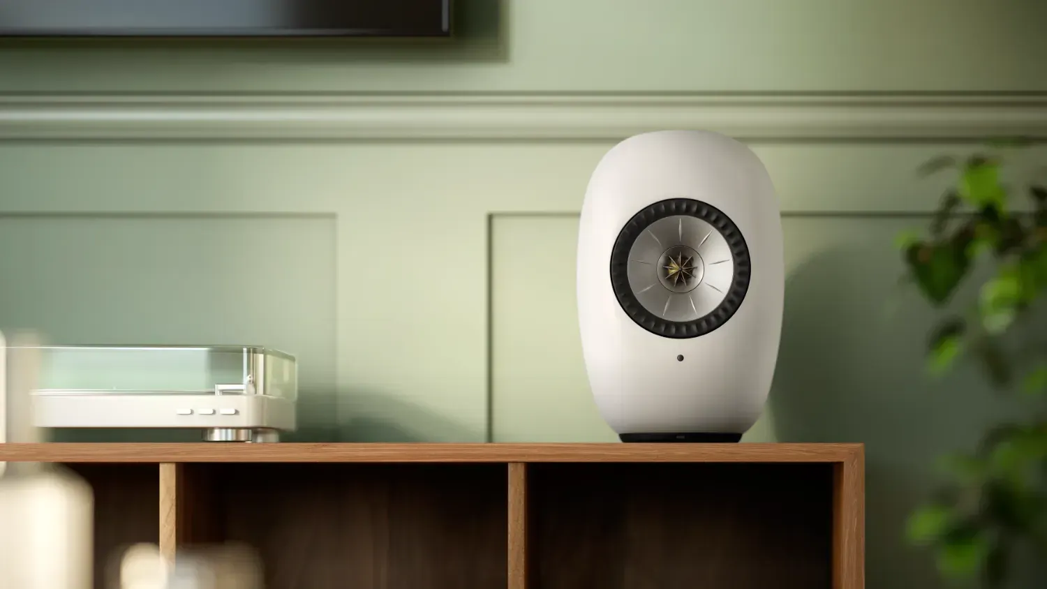 The new KEF LS LUXE on a shelf next to a turntable