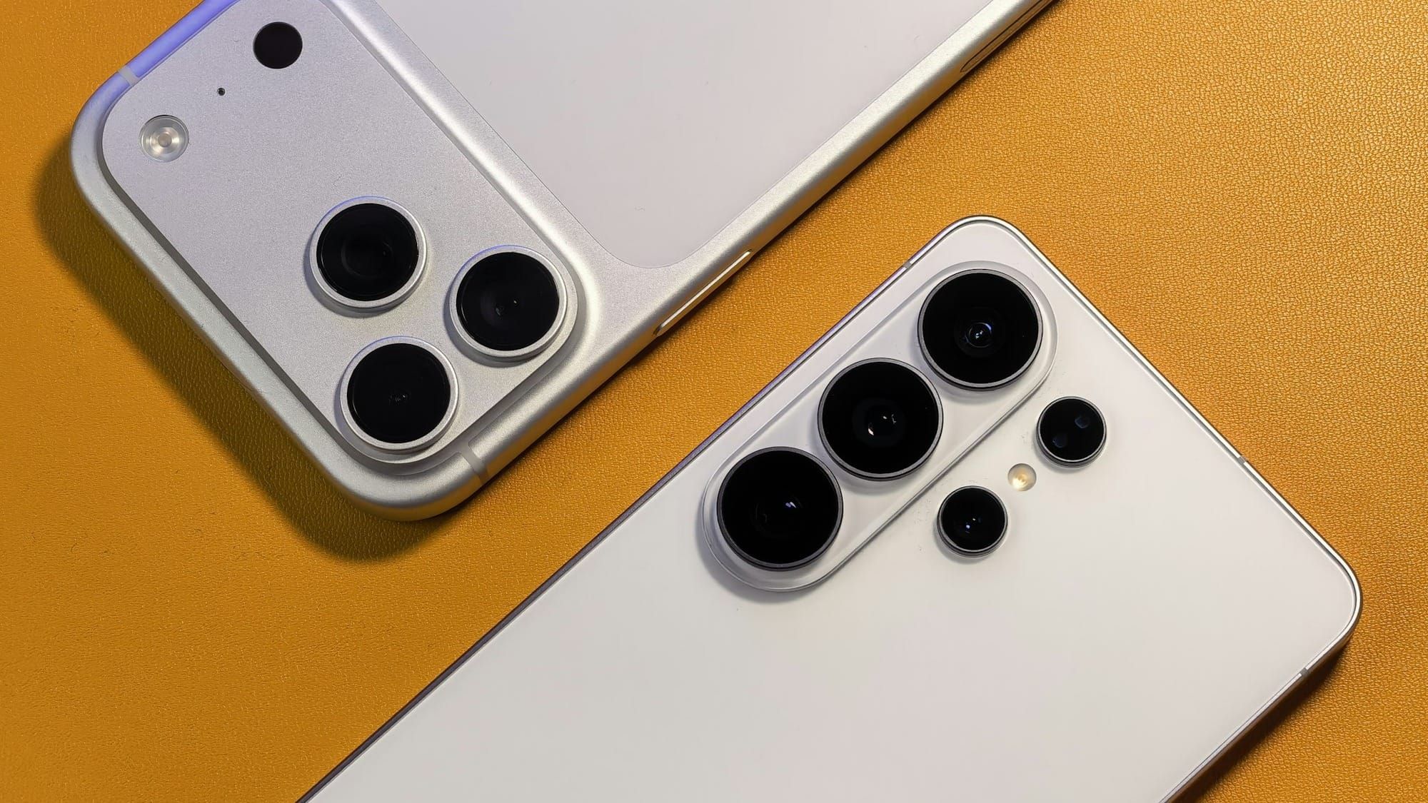 An iPhone and a Samsung phone side by side, face down on an orange background