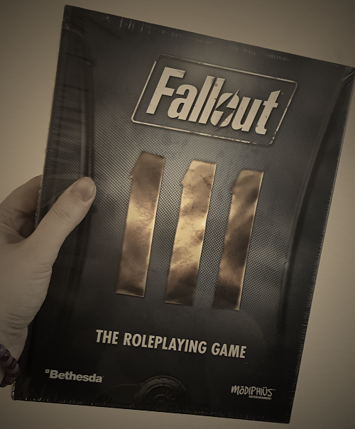 Picture of the sourcebook for Fallout: The Roleplaying Game. The book is designed like the back of a Vault jumpsuit, blue with the golden appliqued number of the '111' Vault.