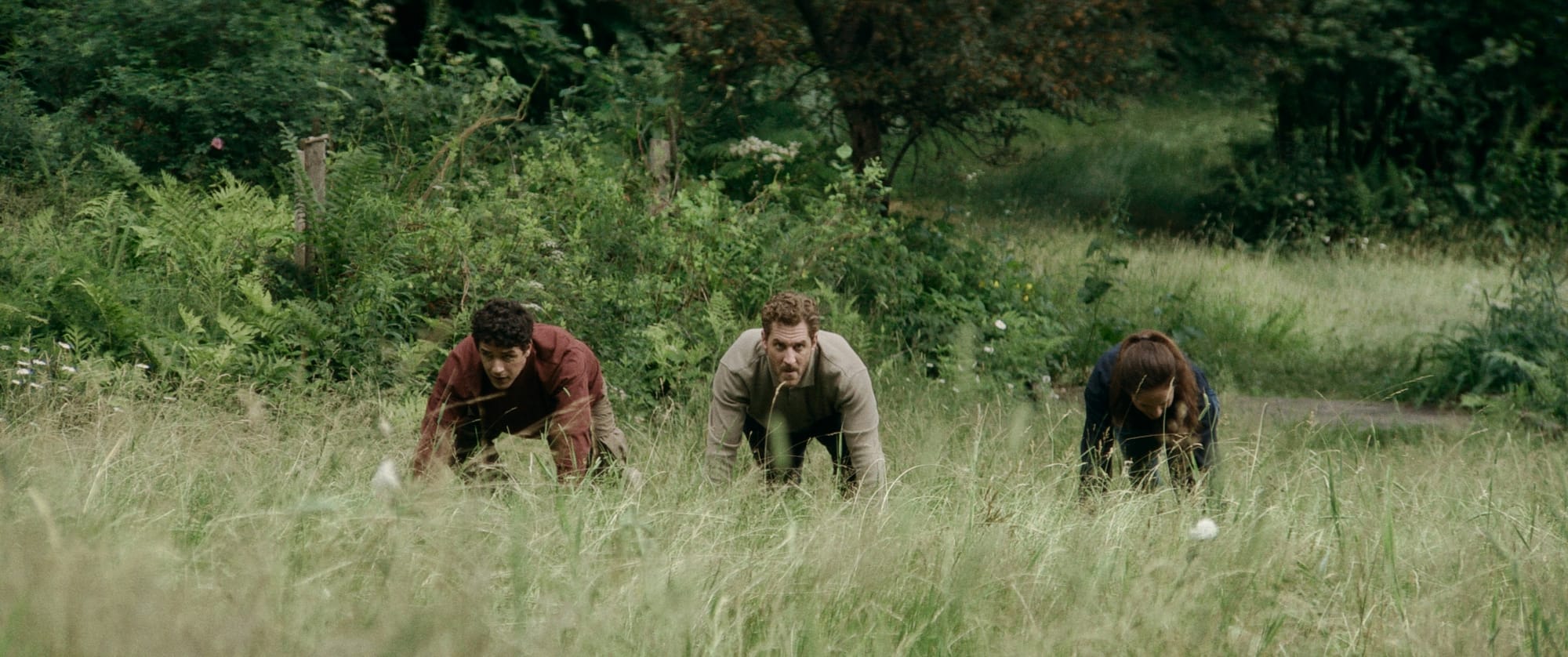 Eli, Lawrence and Philip take their marks in the 'Balance' race as part of their family's 'Best Boy' competition. The field is wild and overgrown; Eli looks pensive, Lawrence stoked to compete and Philip looks down and away; either disillusioned or concentrating.