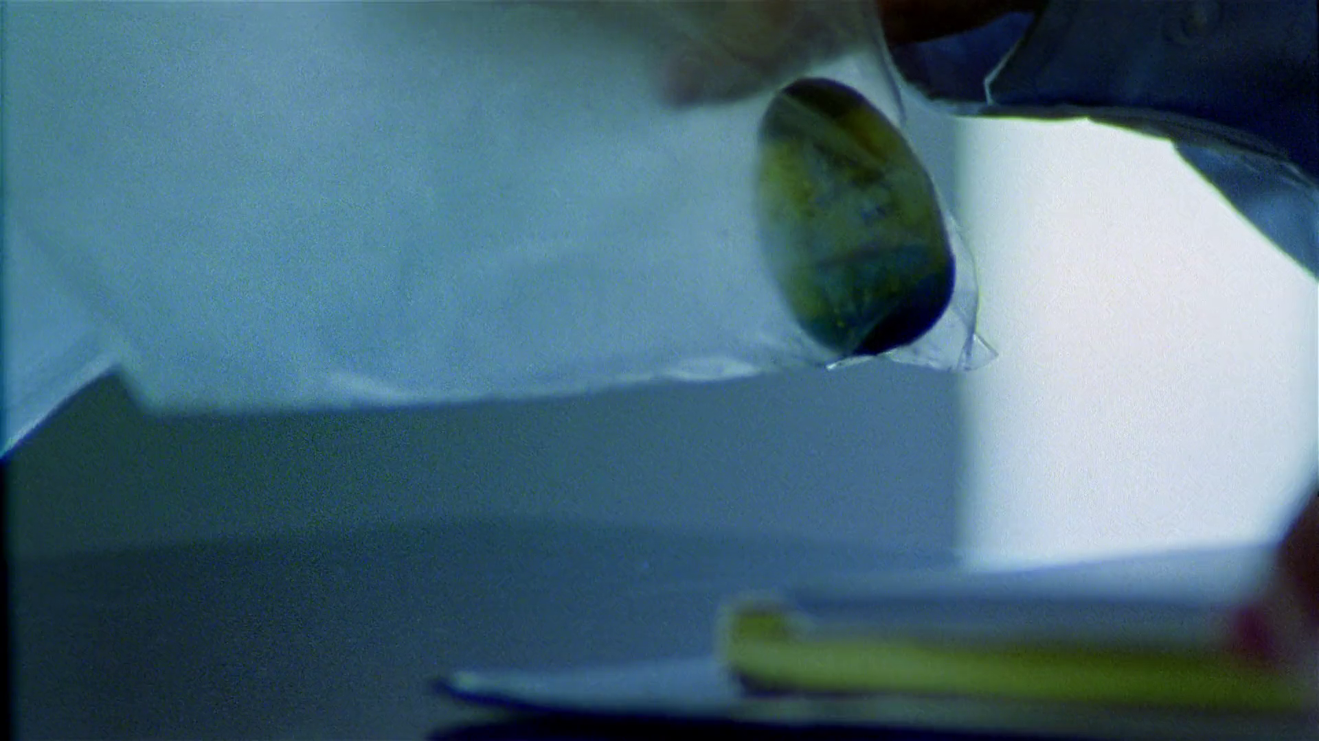 A close-up of a Weeble Wobble toy coated in a thick, grey layer of rapidly aged protein film after being removed from the machine.