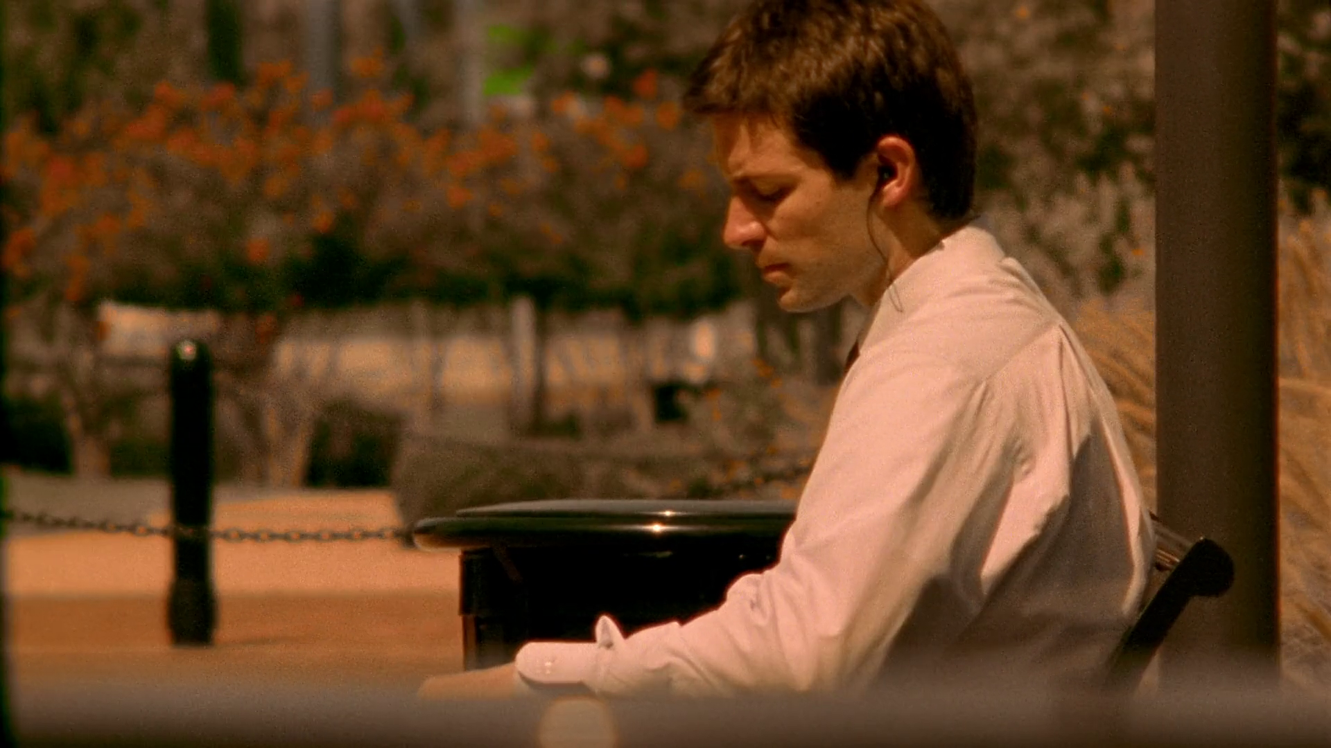 A close-up of Aaron sitting in a car, wearing a subtle electronic earpiece as he listens to recorded conversations.