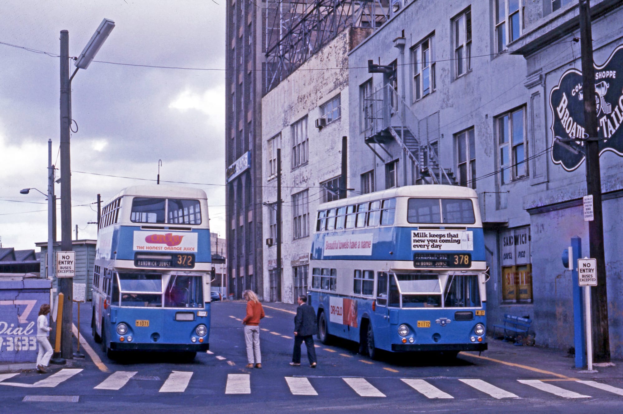 Two blue double-decker buses idling in a terminal, waiting to distribute labor across the city grid.