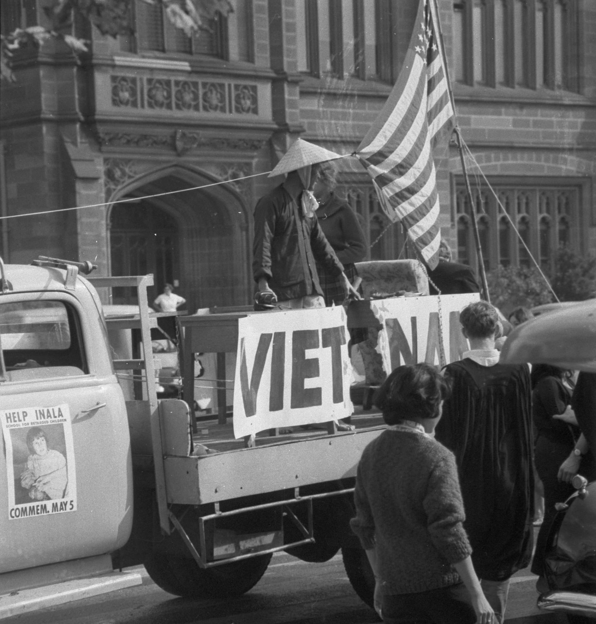 A protest float on a truck featuring an American flag and a 'VIETNAM' sign, demonstrating the ideological conflicts within the university apparatus.