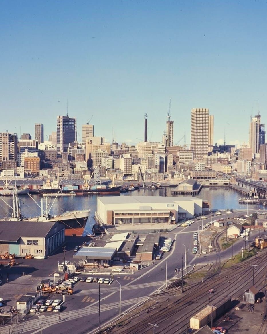 A sprawling view of industrial wharves and warehouses at Darling Harbor, the physical architecture of localized capital.