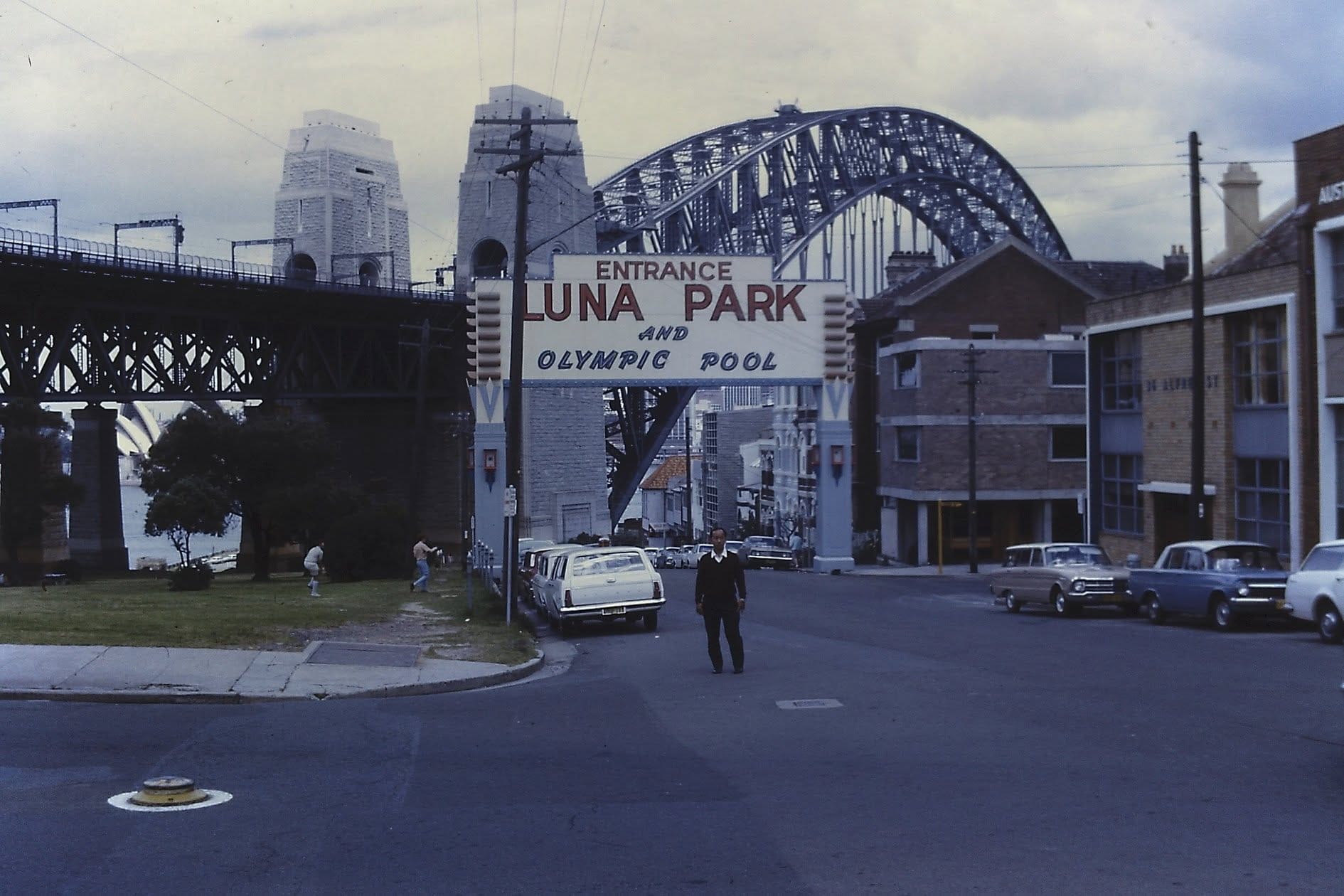 The imposing, grinning facade of Luna Park beneath the Sydney Harbour Bridge, a monument to localized spectacle.