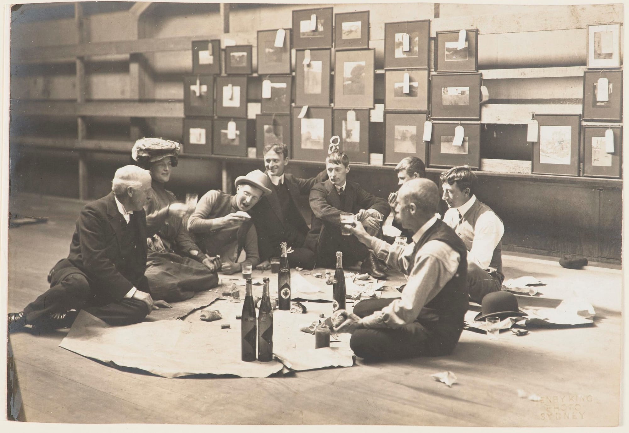 Black and white photograph of wealthy men sitting on the floor drinking, insulated from the material realities of the working class.