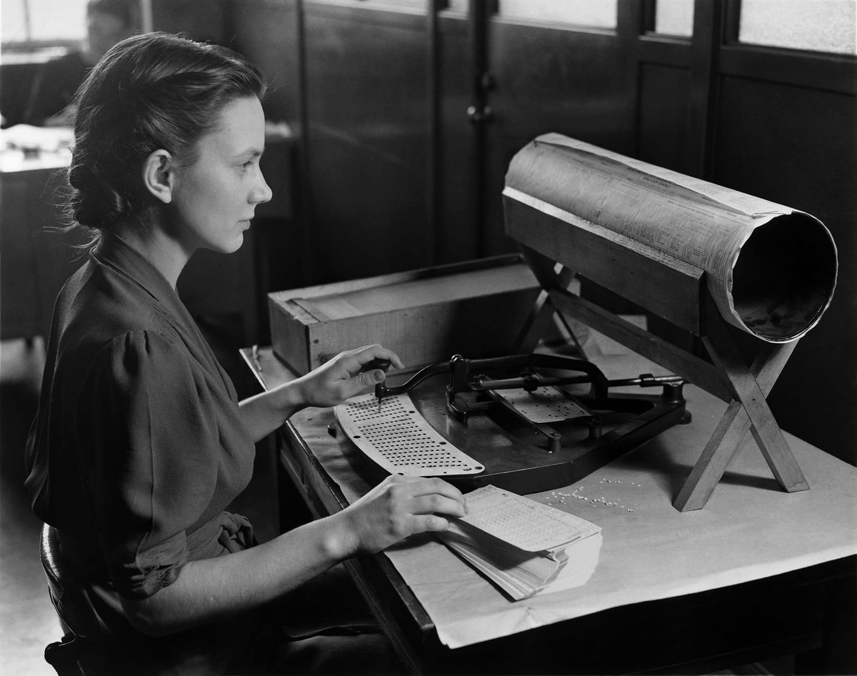 A woman operates a manual pantograph punch in a vintage photo, using a stylus to punch holes in a data card, illustrating the physical and industrial labor of early computing.
