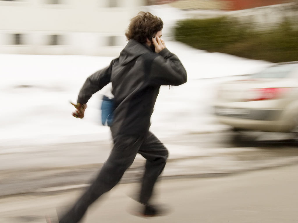 Man running down street with a phone to his ear; MCAT registration date