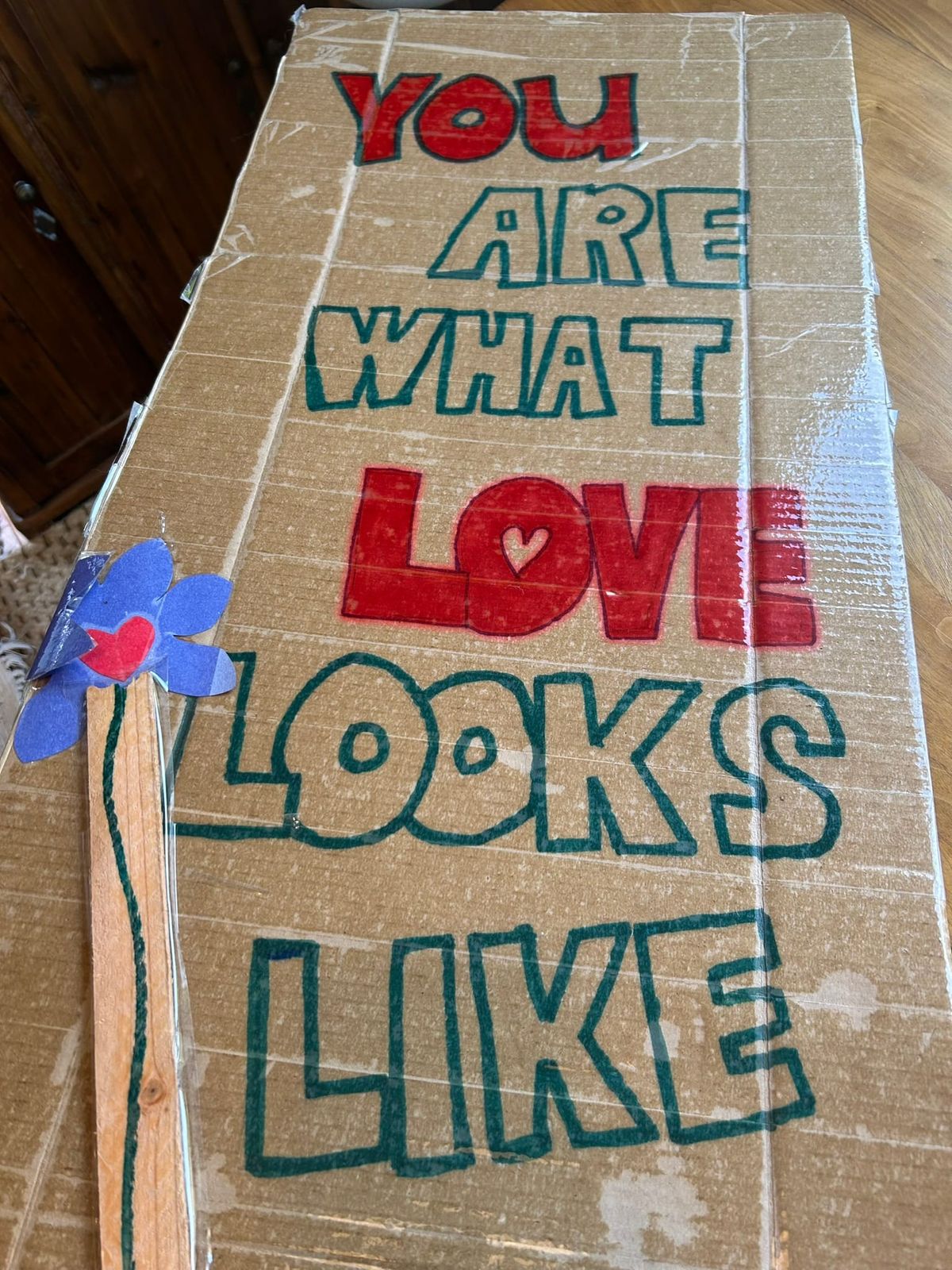 Photo of a cardboard sign with handwritten words that say, "You are what love looks like."