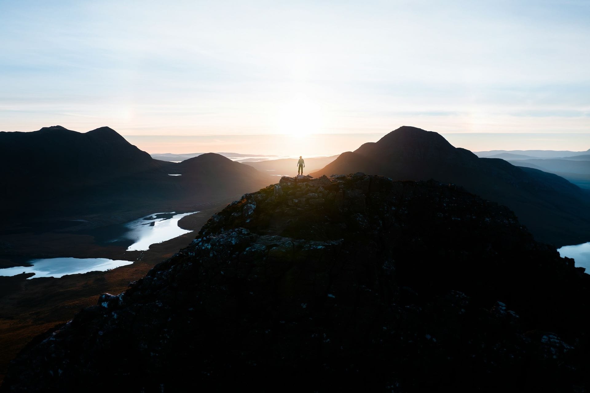 Persona isolata in cima a una vetta ammira un paesaggio montano sublime al tramonto, sperimentando il decentramento cognitivo.