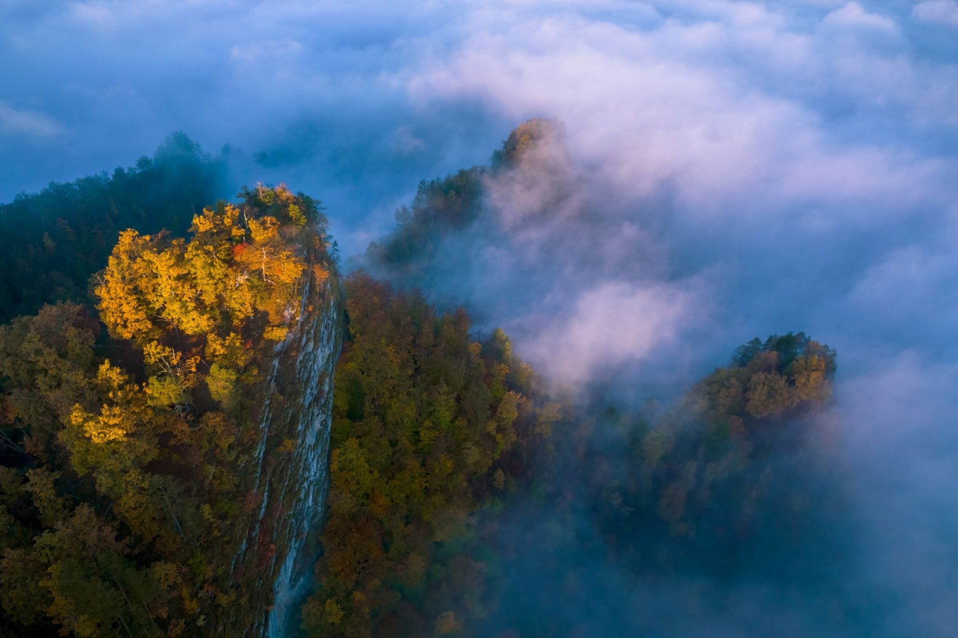 Parete rocciosa al tramonto di fine inverno con il paesaggio completamente avvolto da basse nuvole, teatro selvaggio per superare i propri limiti.