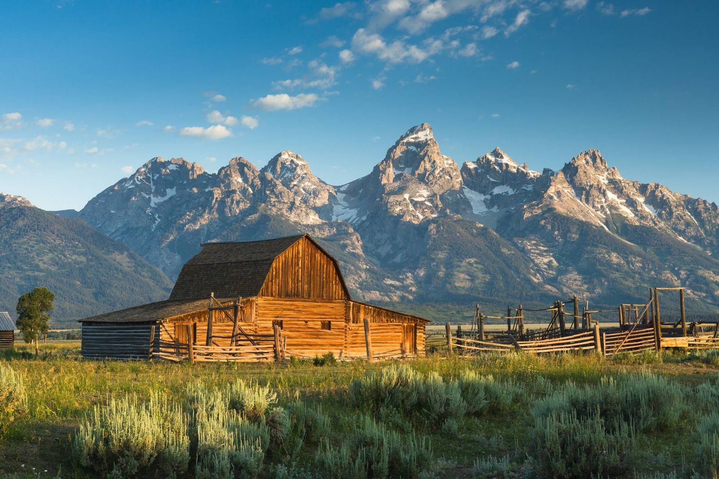 Fienile di legno a Mormon Row con la catena del Grand Teton sullo sfondo, nel Wyoming, alla luce del mattino