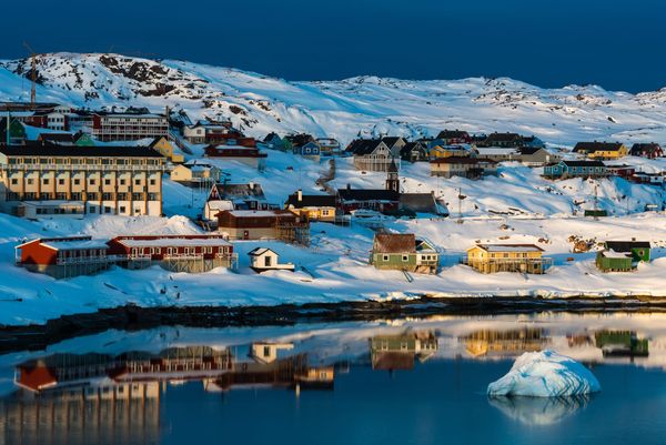Le tipiche case colorate di Ilulissat, Groenlandia, con montagne innevate sullo sfondo.