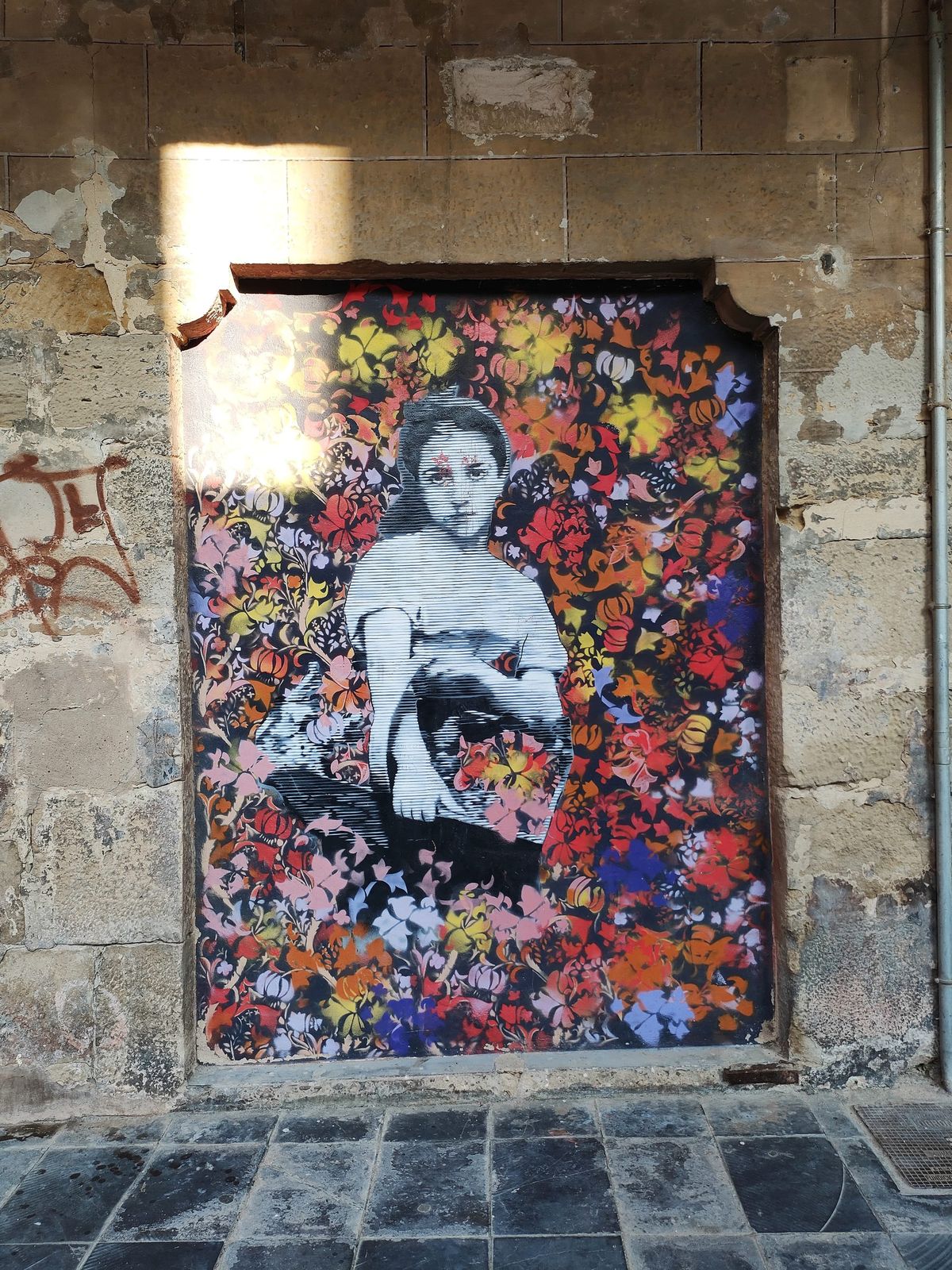 collage de pared donde se entrevé una chica joven con una cesta en brazos sobre un mural de flores muy coloridas