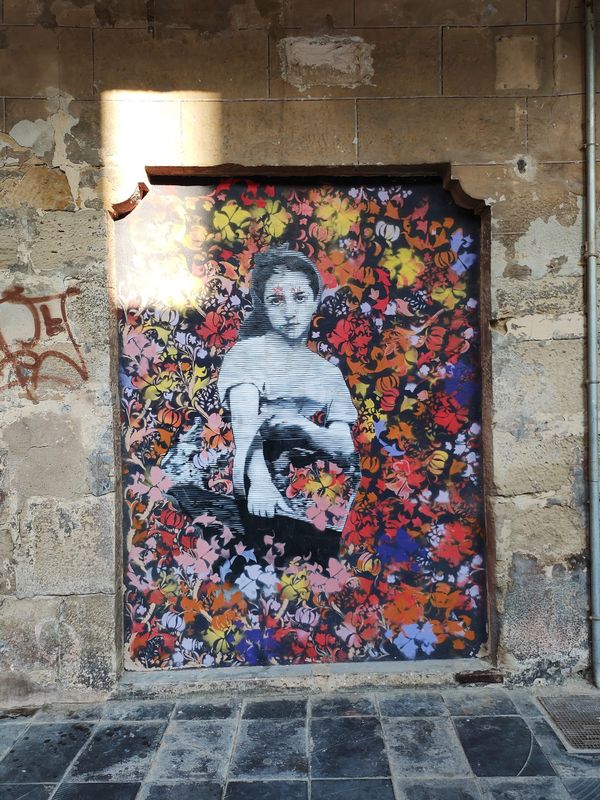 collage de pared donde se entrevé una chica joven con una cesta en brazos sobre un mural de flores muy coloridas