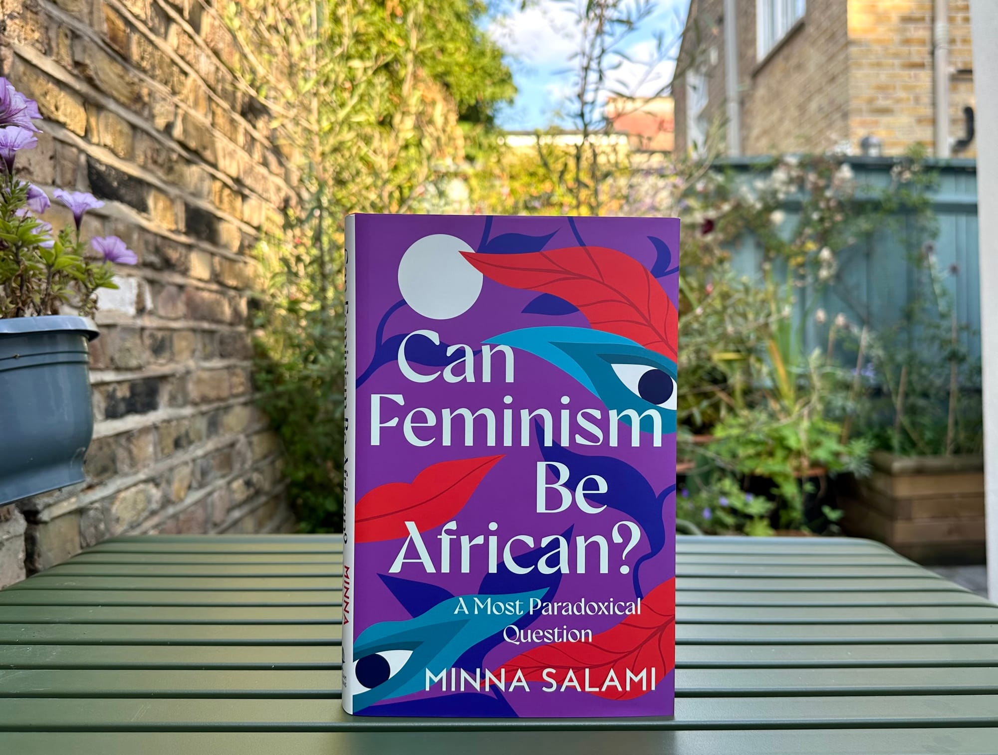 Photo of the book Can Feminism be African? by Minna Salami, taken in a garden.