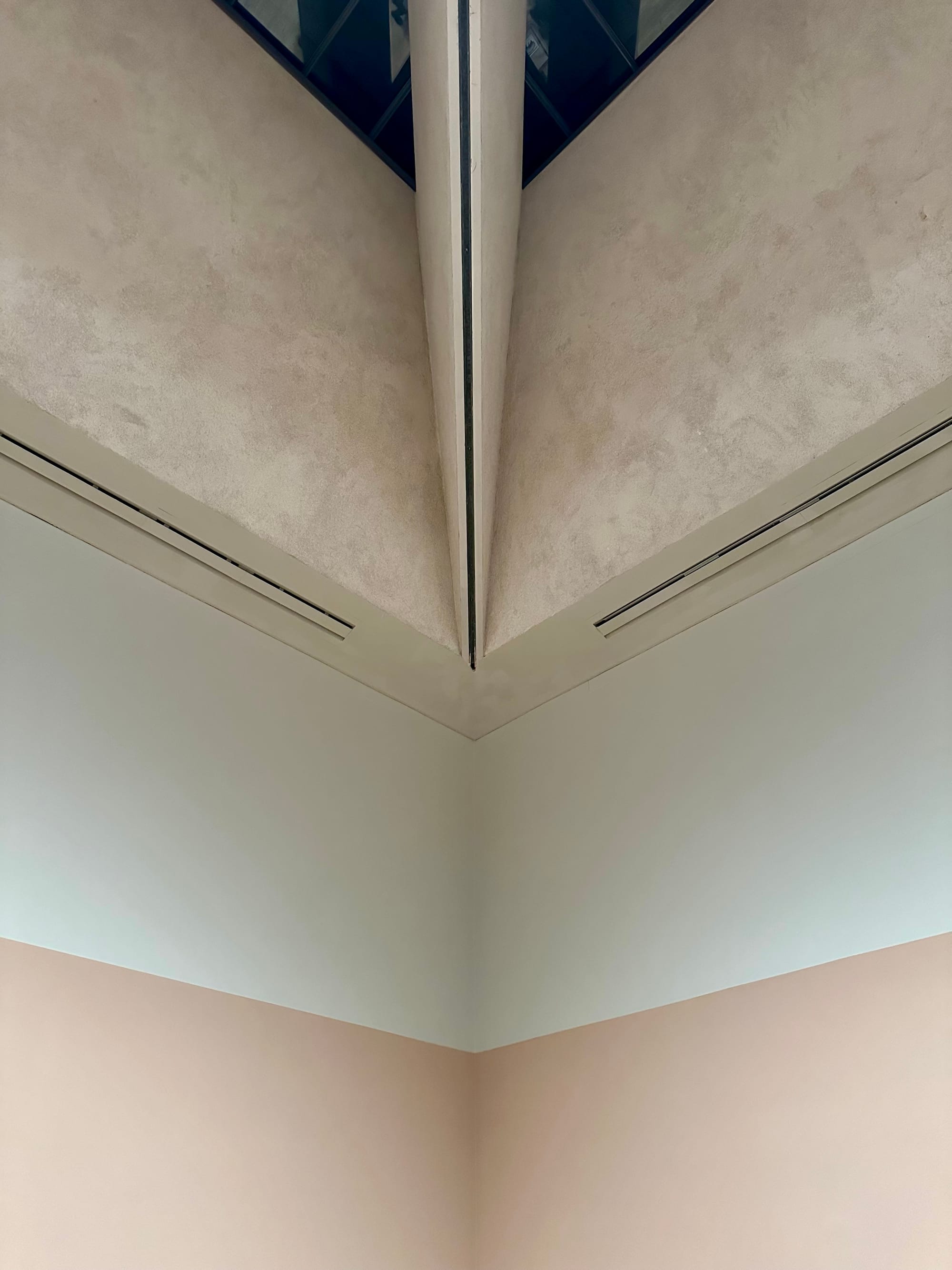 Detail of a gallery interior with walls painted in thick bands of dusty pink and light grey.