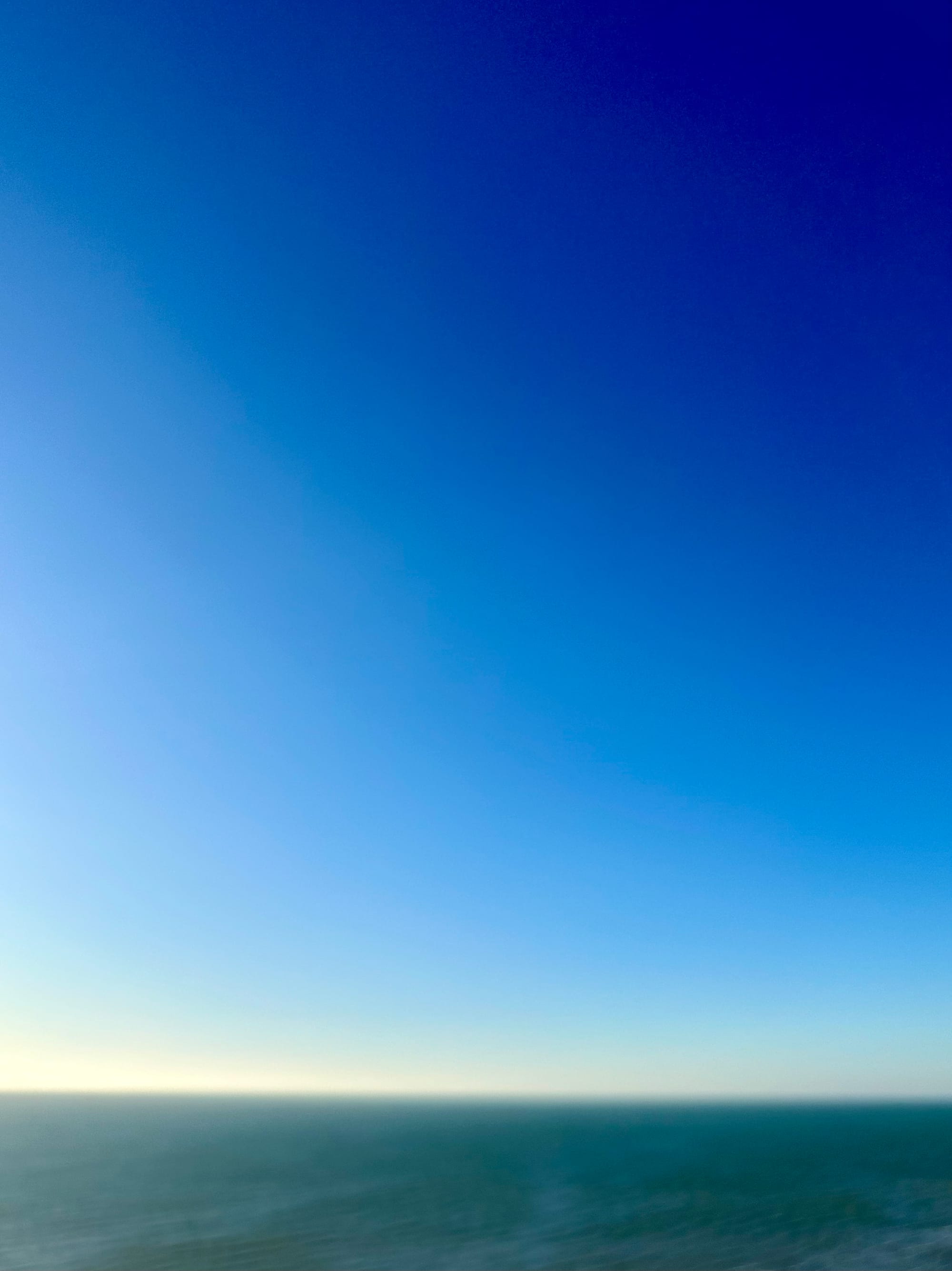 Photo of a clear blue sky over a clear blue sea.