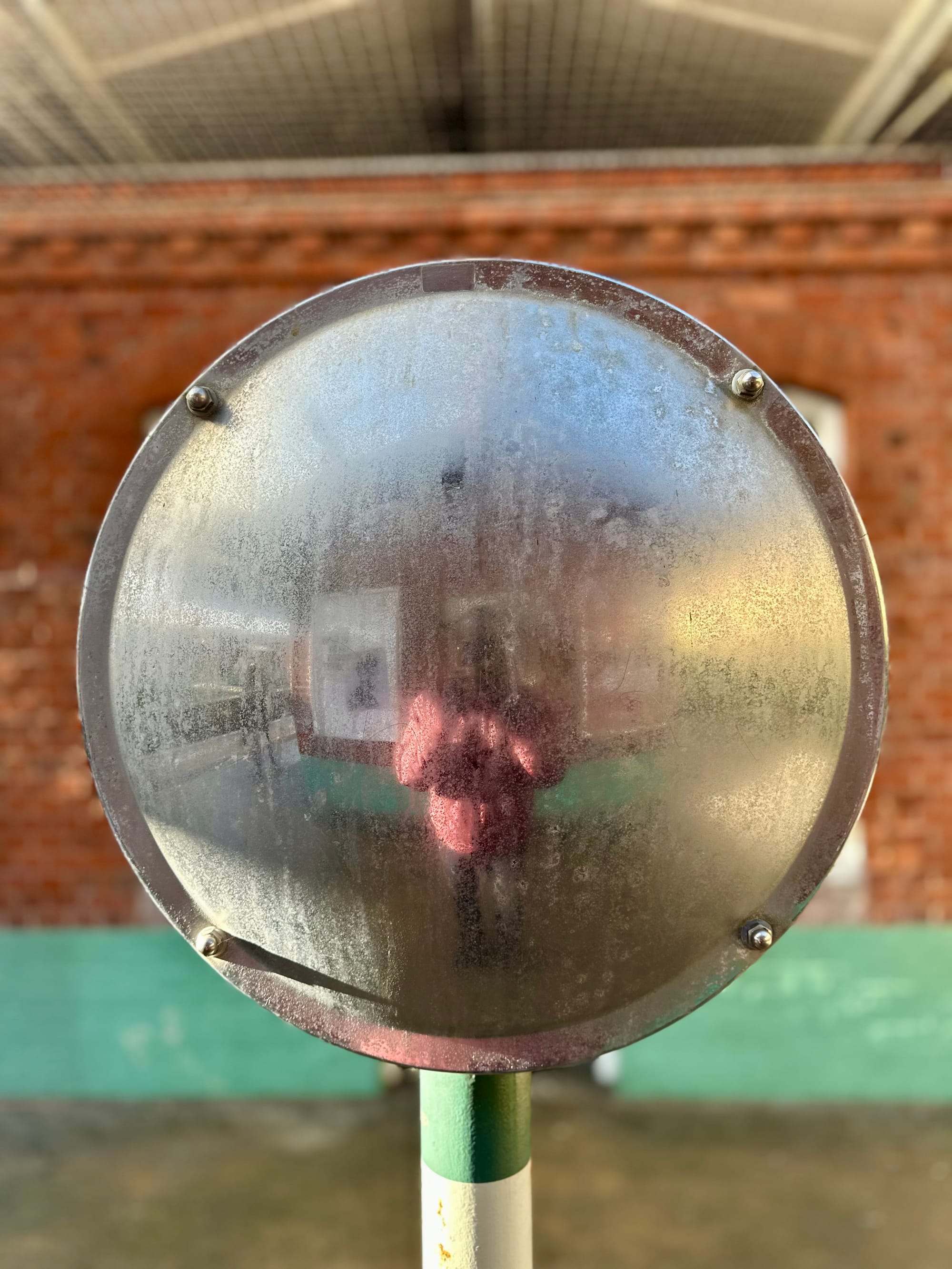 Selfie in a dirty circular mirror at Worthing station.
