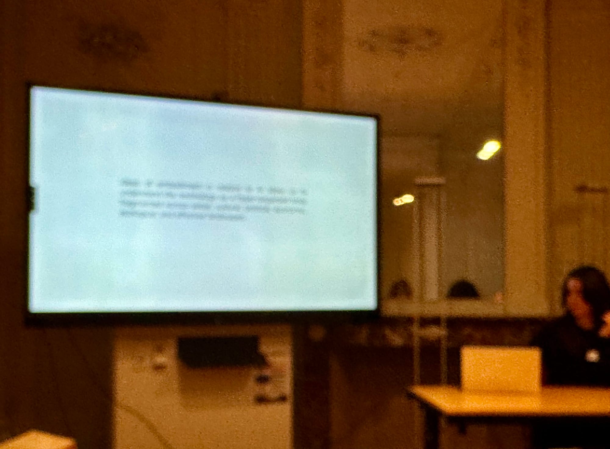 Blurry photo of a symposium lecture in an ornate eighteenth century room.