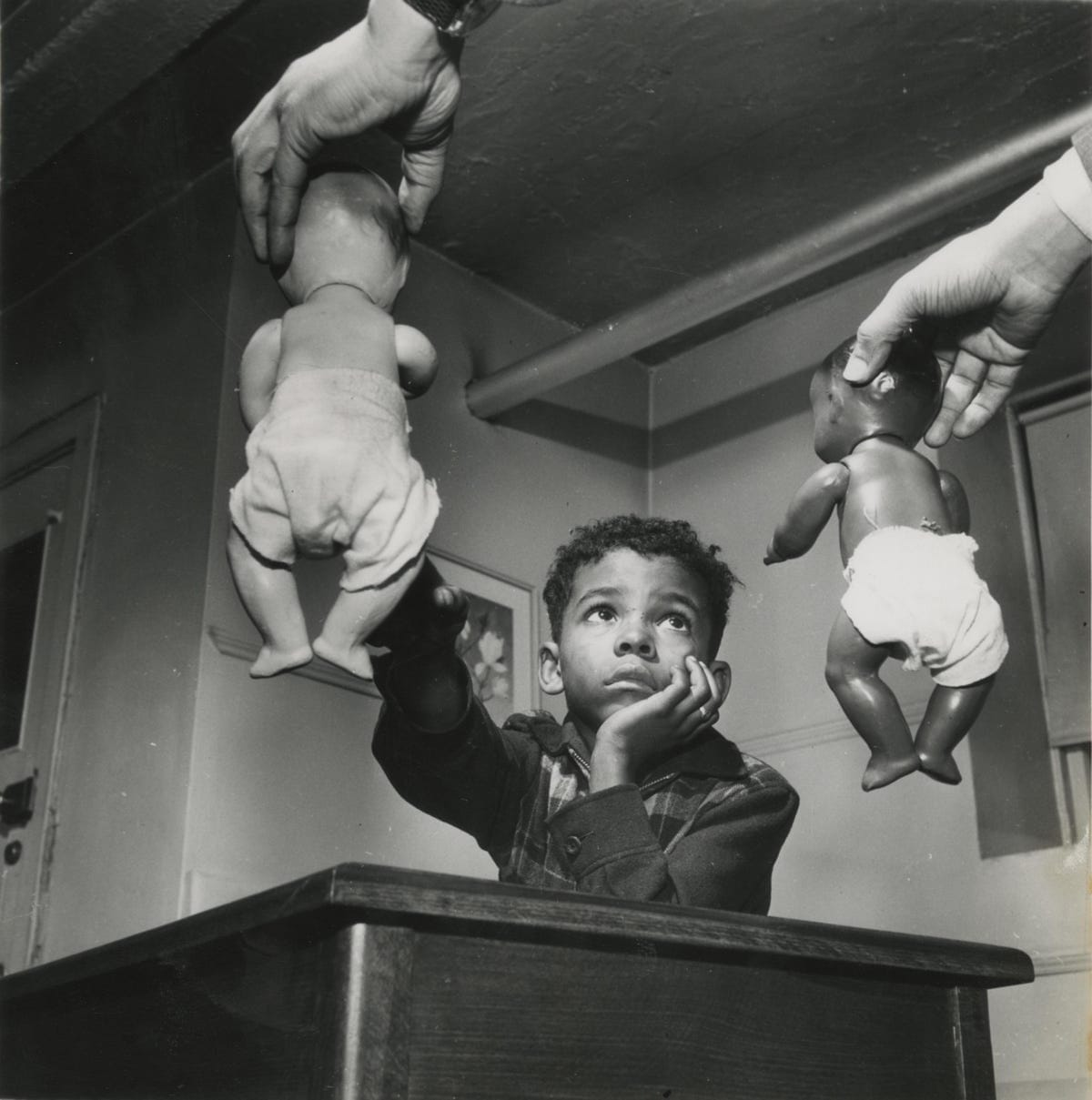 Famous photo of black infant being shown two dolls, one black and the other white.