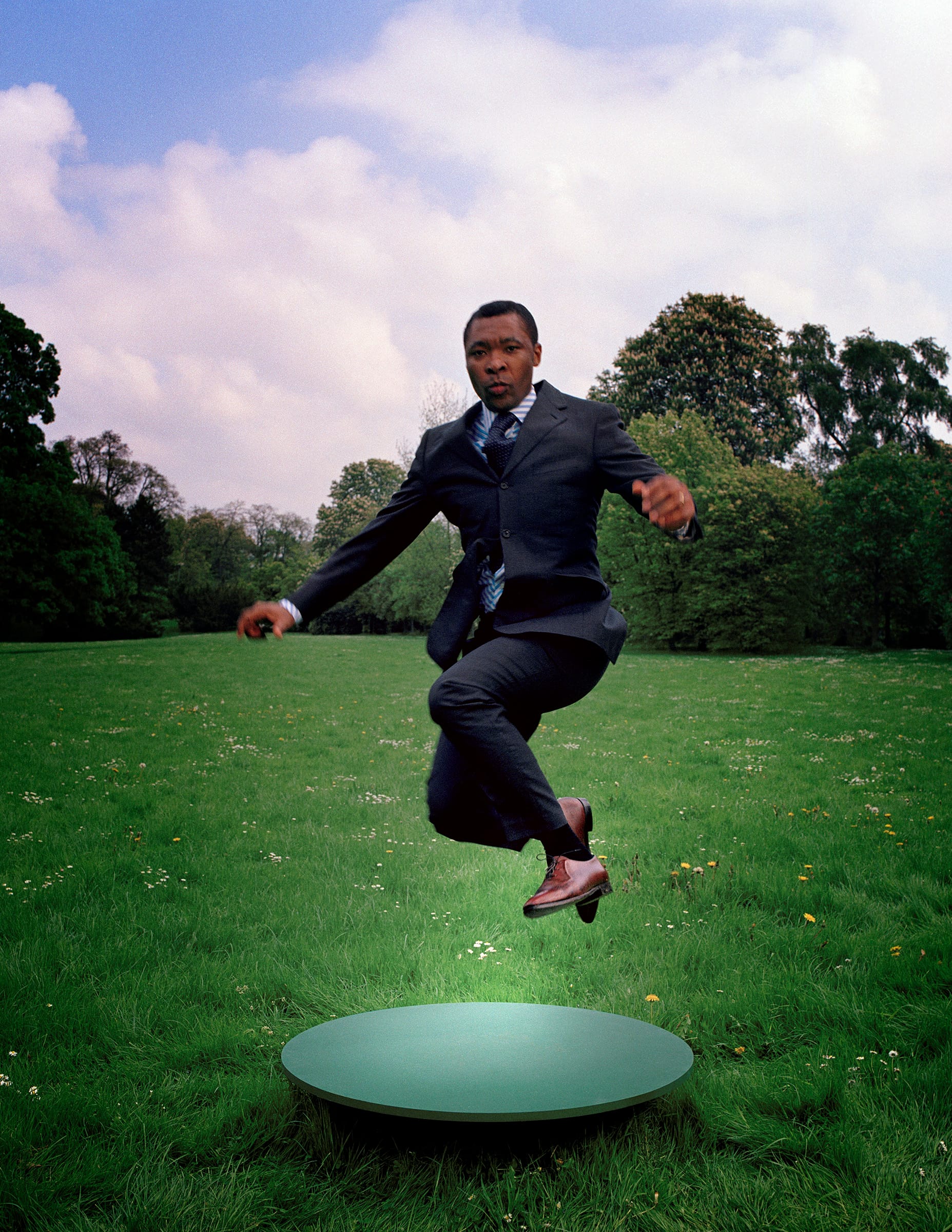 Nigerian curator Okwui Enwezor caught mid-leap above a circular pad.