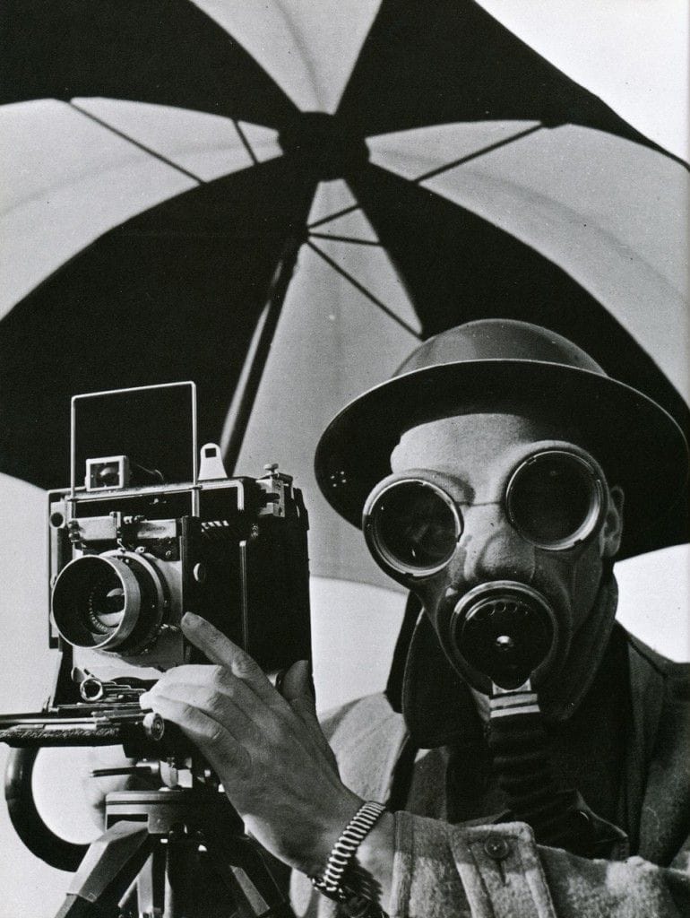 Man in gas mask poised next to a camera, taken by Lee Miller.