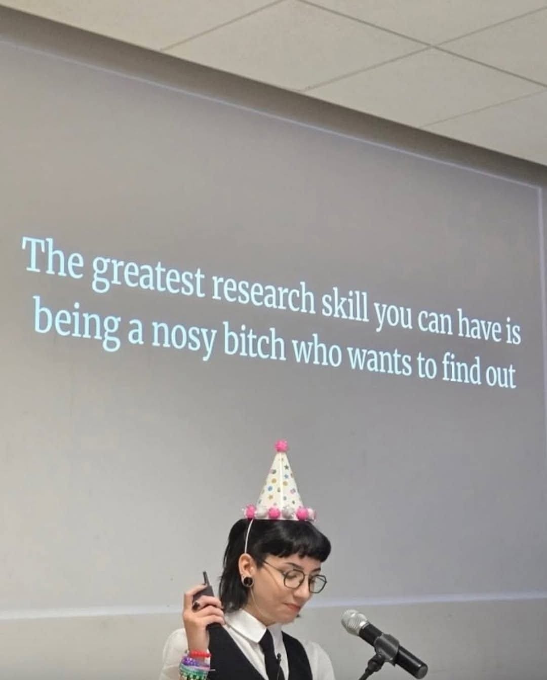 @strange_aeon delivering a lecture in front of a slide which says: The greatest research skill you can have is being a nosy bitch who wants to find out.